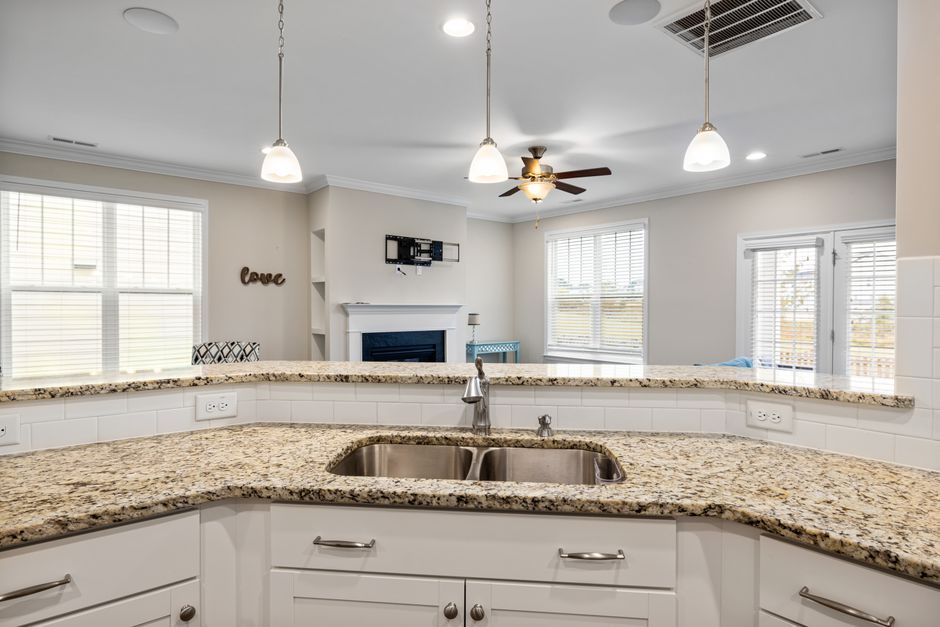 Bright kitchen interior featuring granite countertops, pendant lighting, and a spacious open layout.